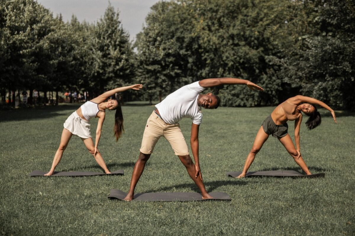 Three people doing yoga in a park.